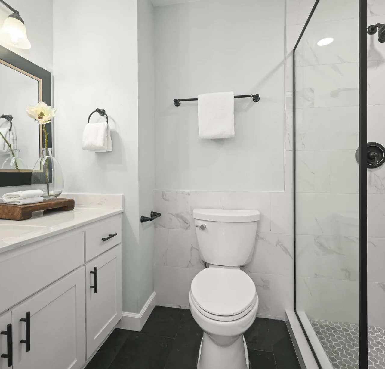 Bathroom with a white vanity, toilet, wood-look flooring and glass shower enclosure