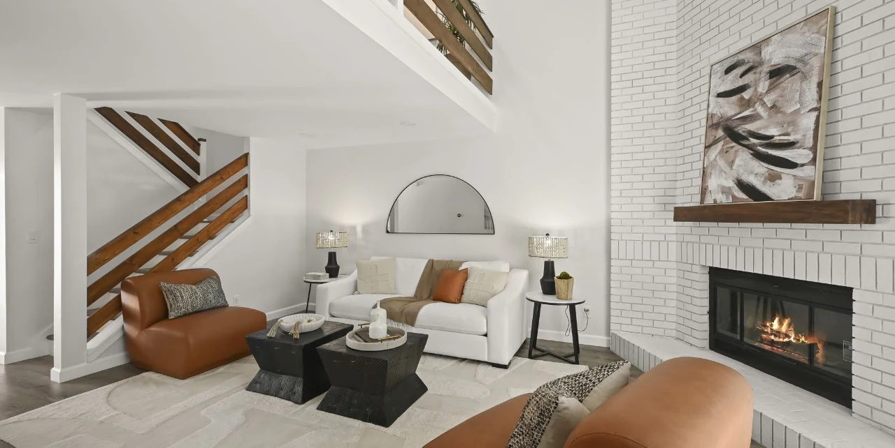 Bright living room with a fireplace, seating area and wood-railed staircase