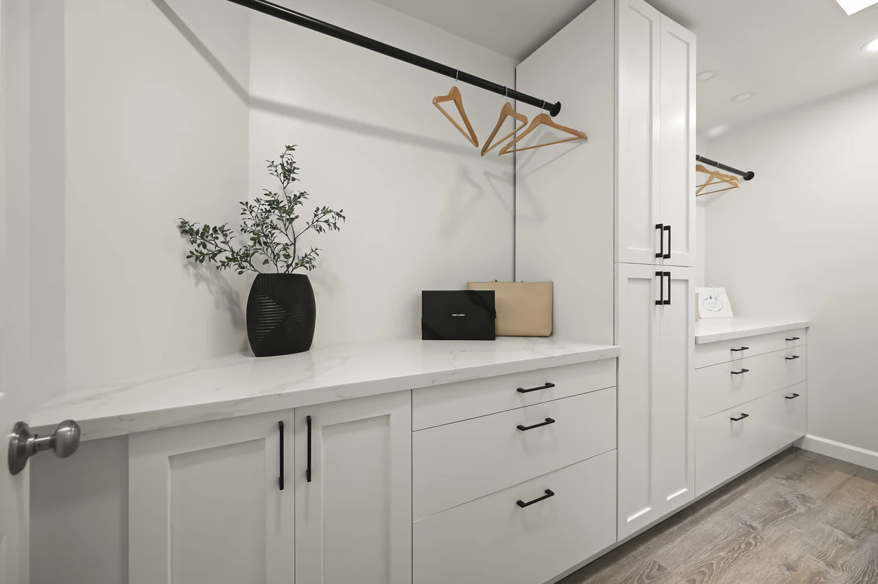 White built-in cabinets beneath a large mirror and geometric ceiling light