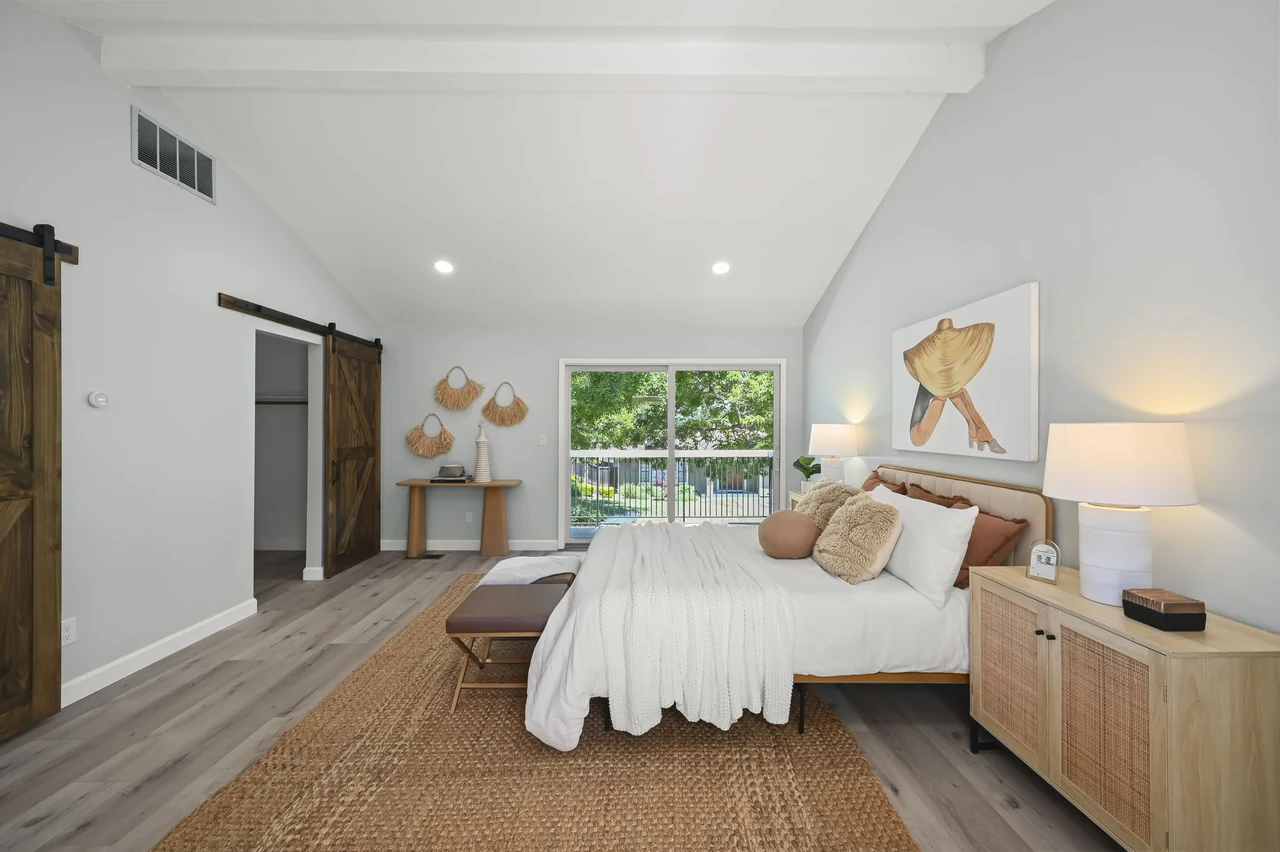 Guest suite looking past the bed toward sliding doors and an outdoor view