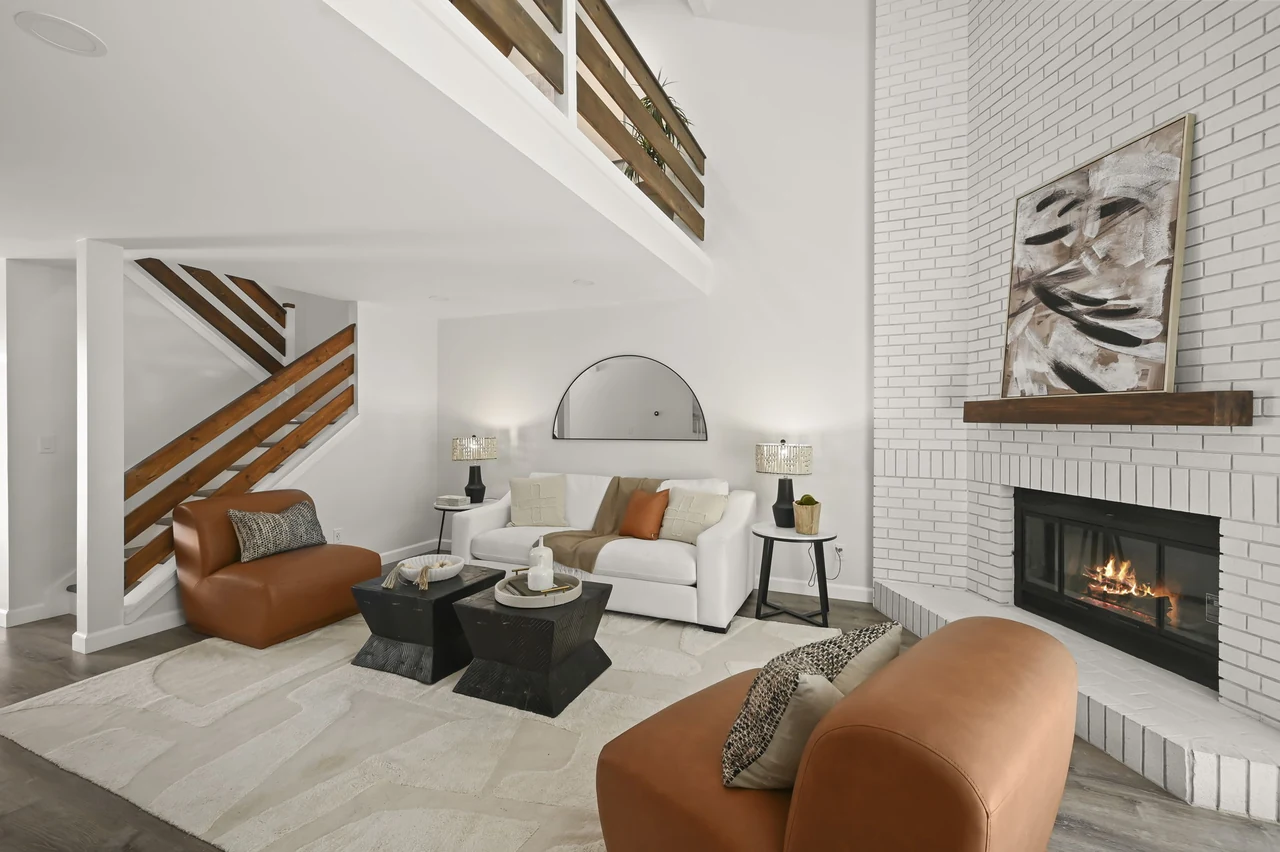 Living room with a fireplace, armchairs and wood-railed staircase