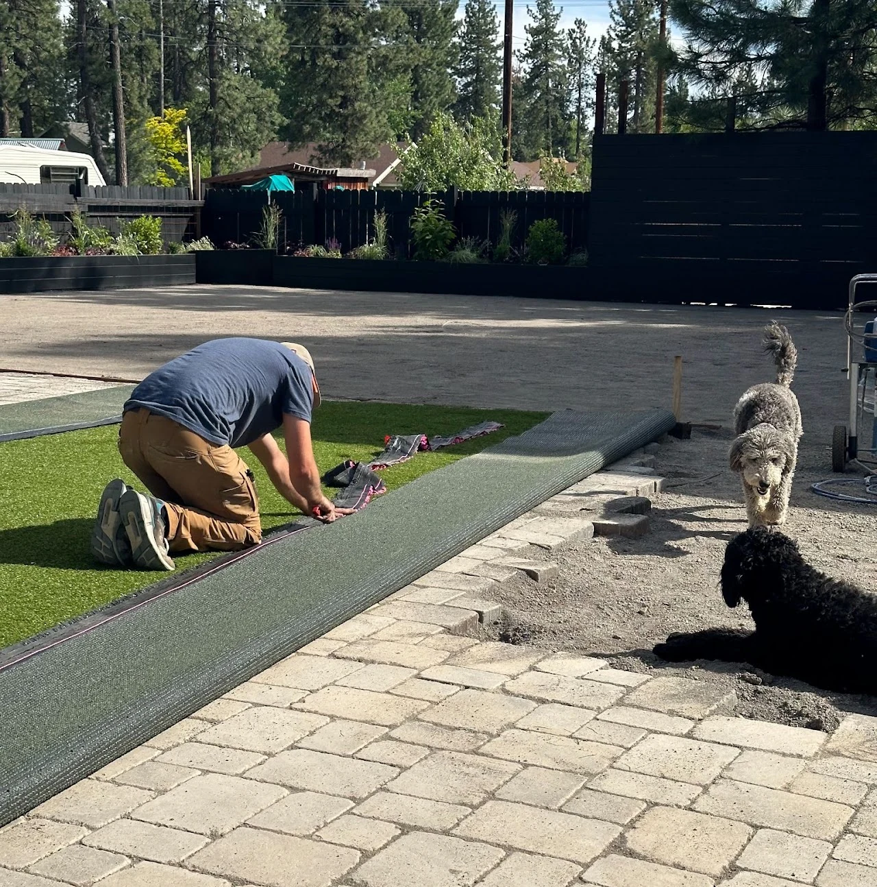 Worker installing lawn edging beside a paver patio